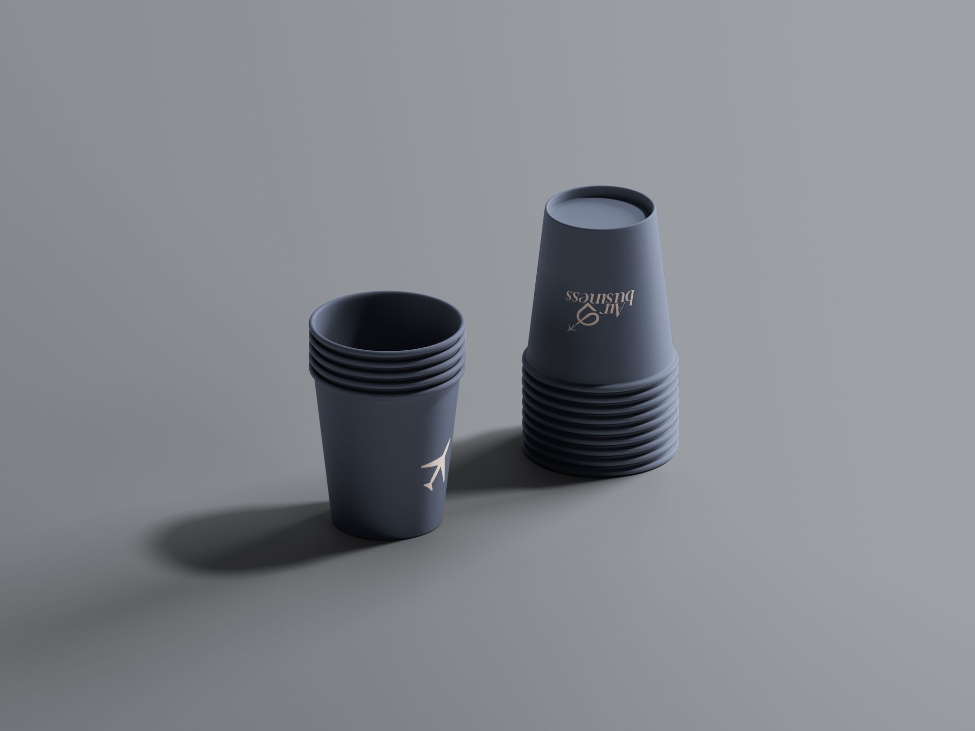 Dos vasos reutilizables de color gris oscuro sobre una superficie gris, uno pequeño y otro más alto con un logotipo.