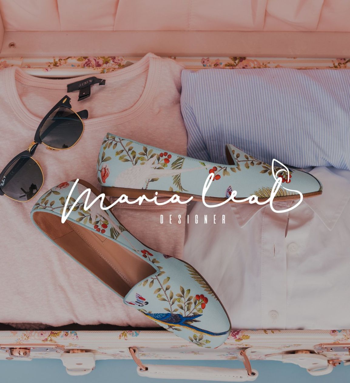 Bandeja floral con gafas de sol y sandalias sobre ropa de cama rosa, con el texto “Maria León” superpuesto.