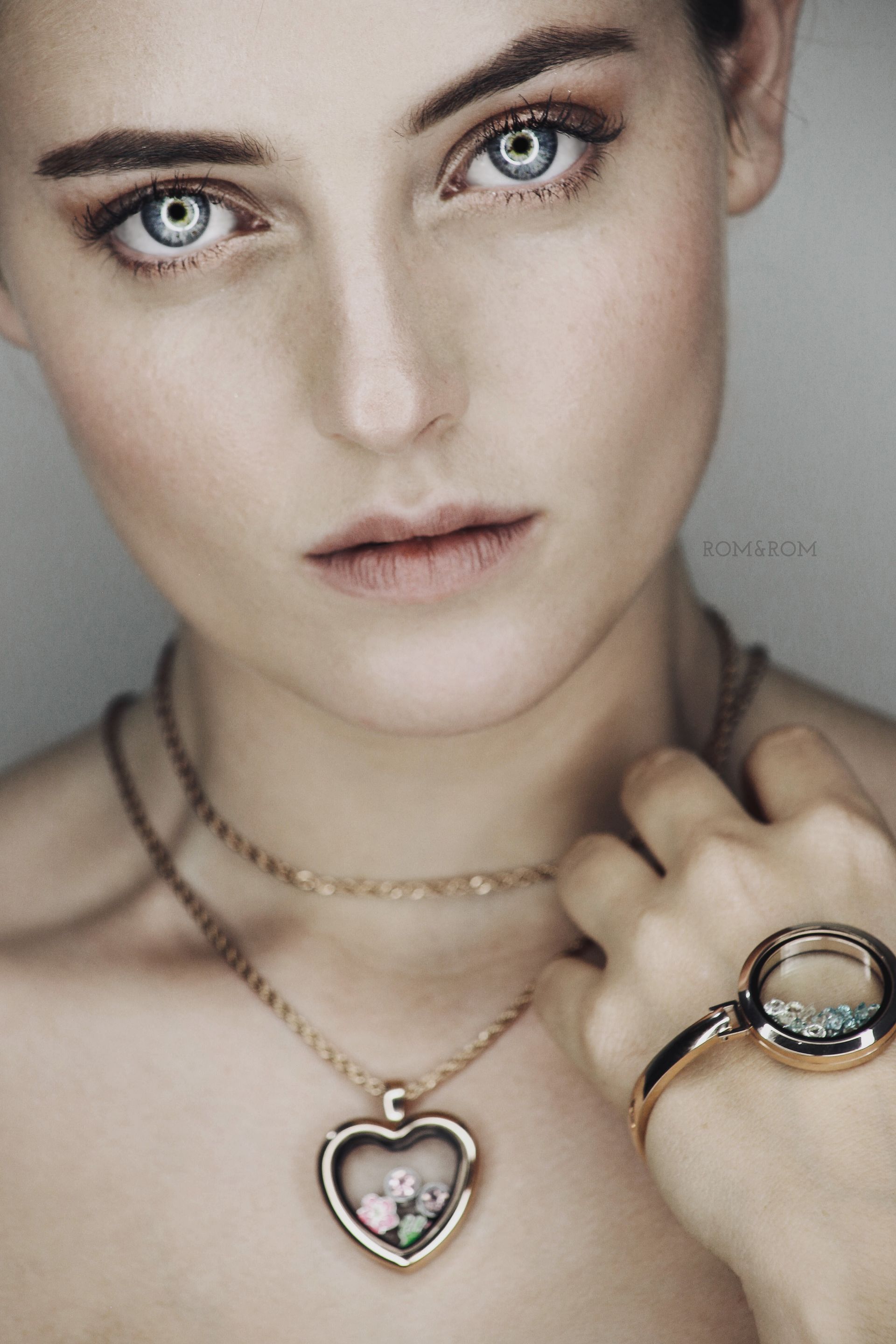Retrato de una mujer con un colgante y una pulsera en forma de corazón, mirando a la cámara.