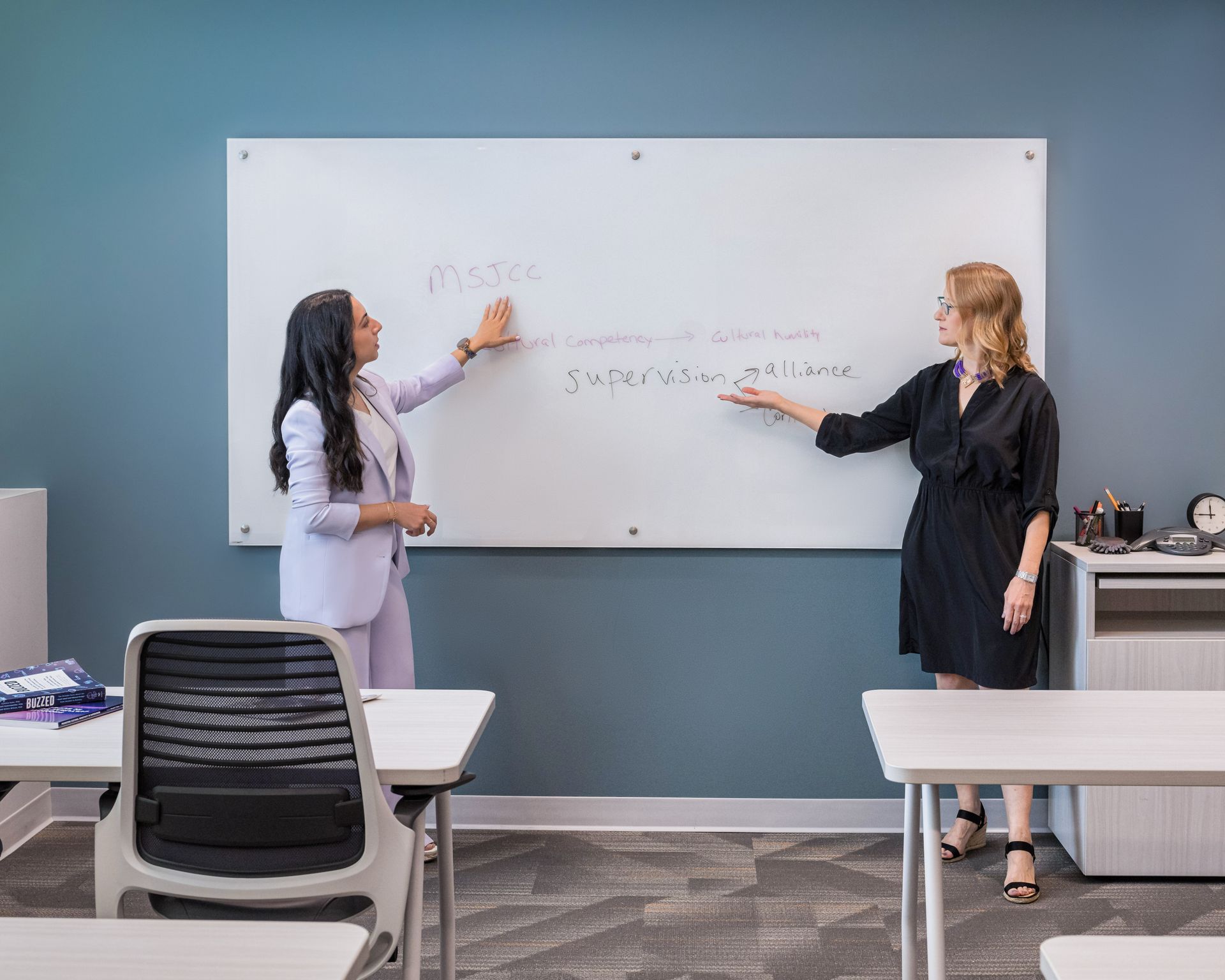 Anjabeen and Arien look at a whiteboard in the classroom.