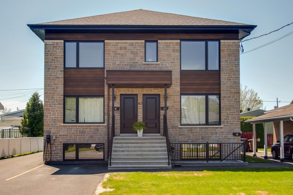 Duplex en briques à deux étages avec portes et garnitures marron foncé, fenêtres et un petit porche avant.