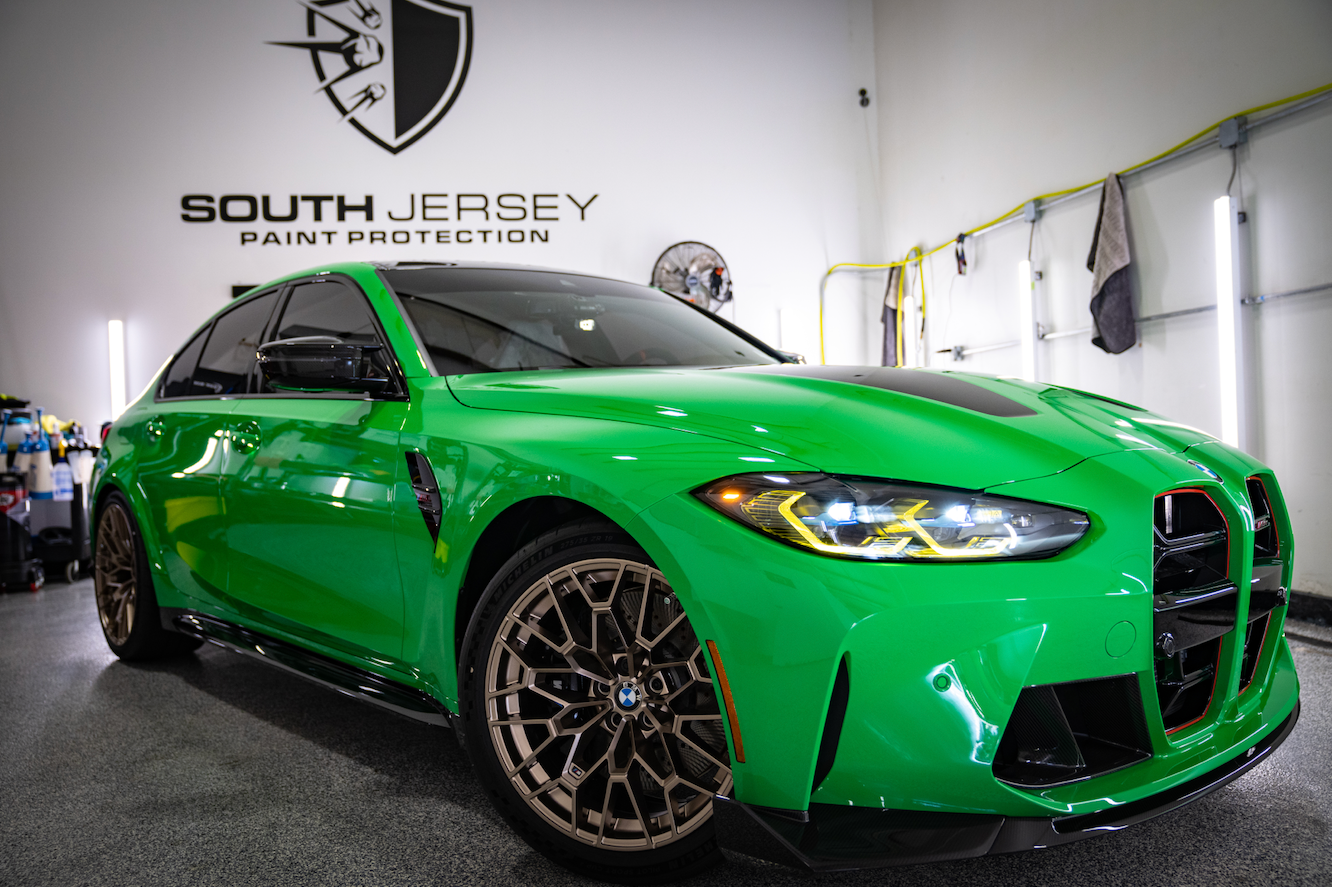 A green bmw m3 is parked in a garage.