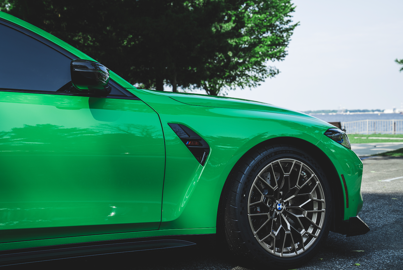 A green bmw m3 is parked in a parking lot.