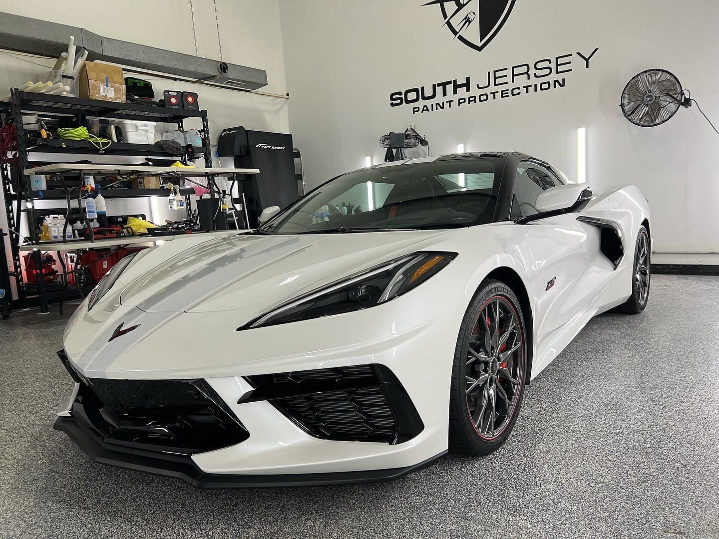 A white corvette is parked in a garage.