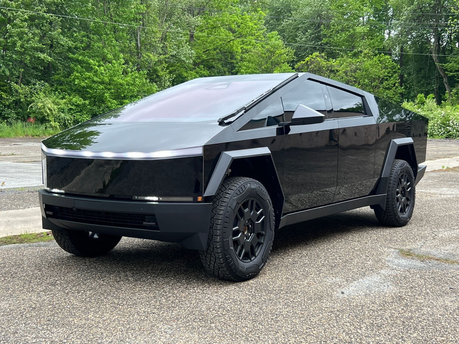 A black tesla cybertruck is parked in a parking lot.