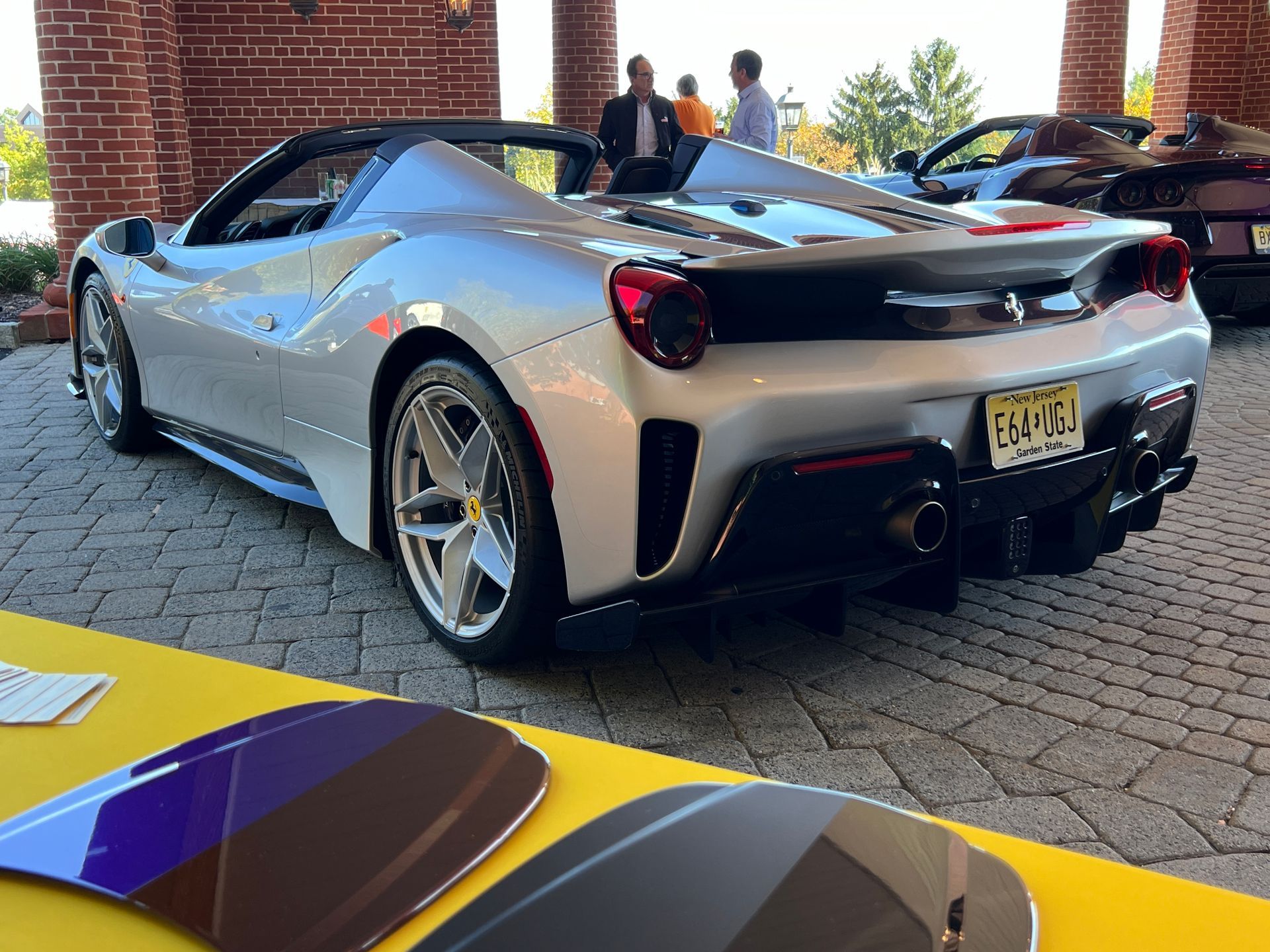 A silver sports car is parked in front of a brick building.