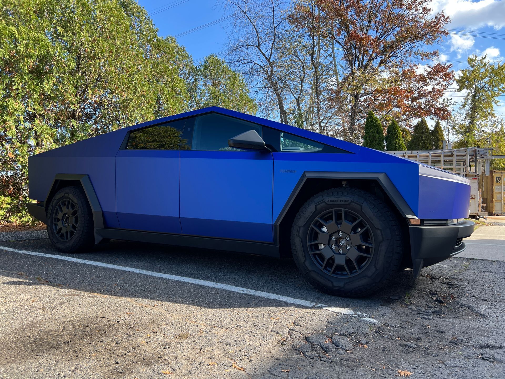 A blue tesla cybertruck is parked in a parking lot.