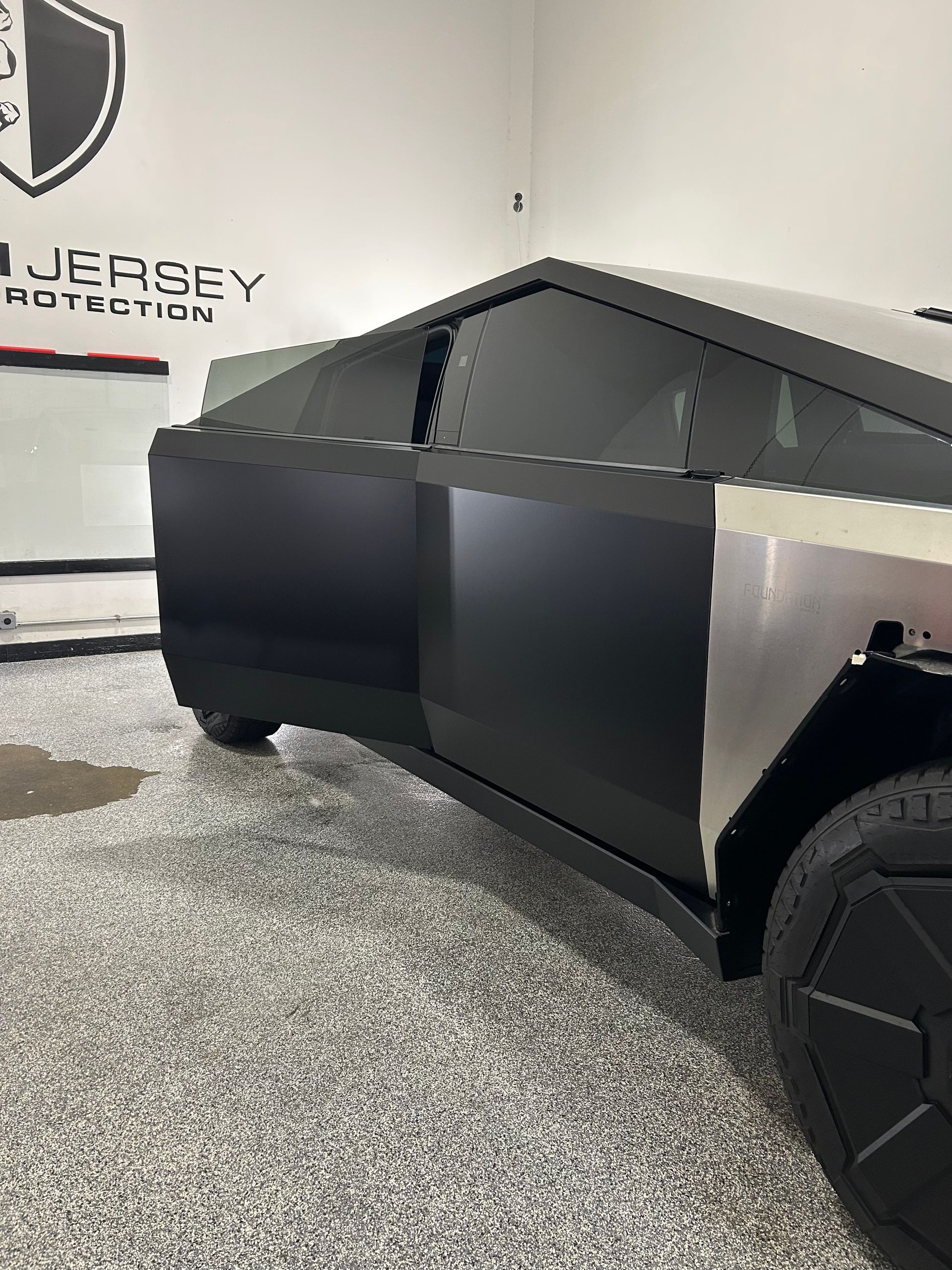A black tesla cybertruck is parked in a garage.