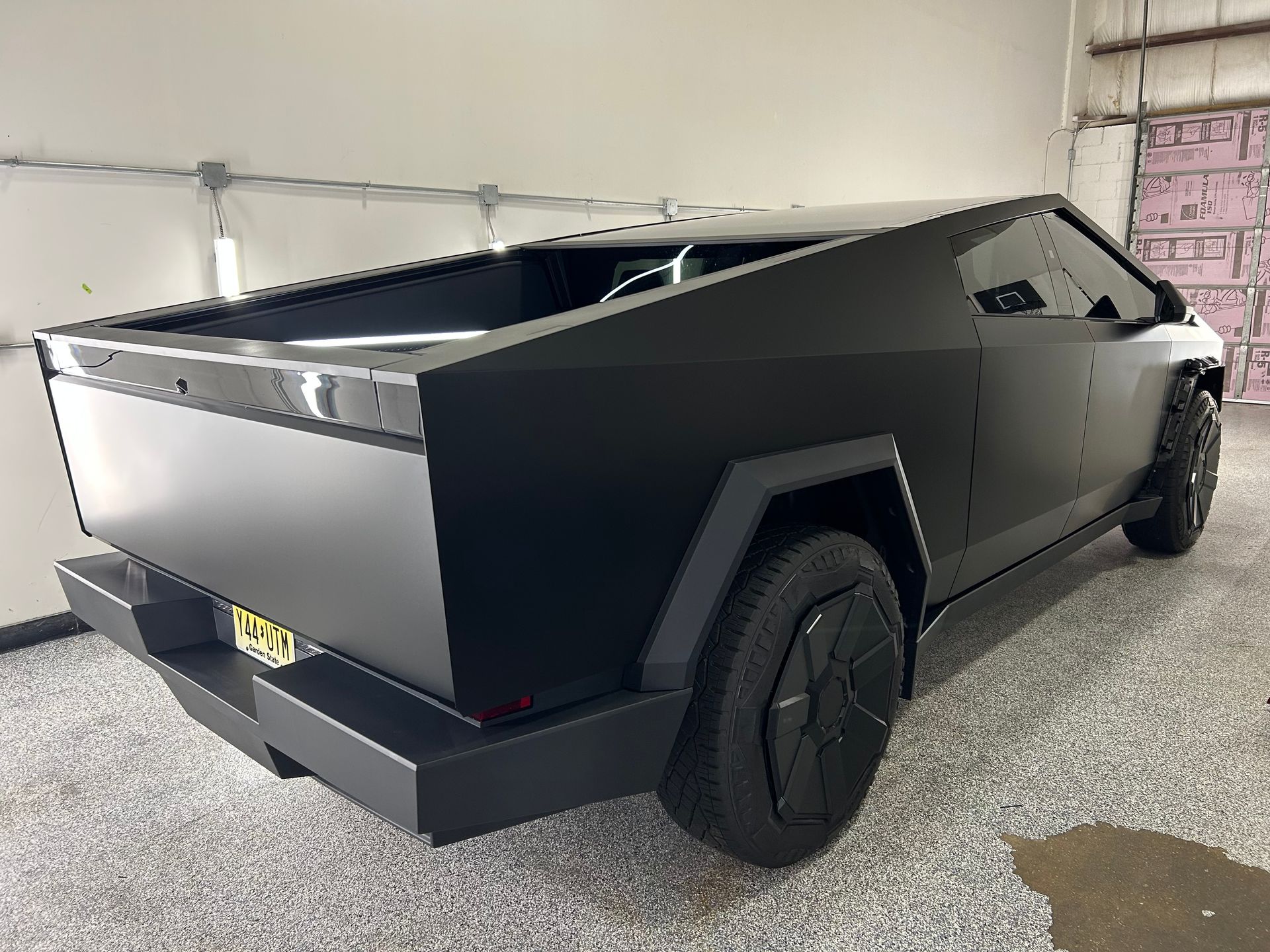 A black tesla cybertruck is parked in a garage.