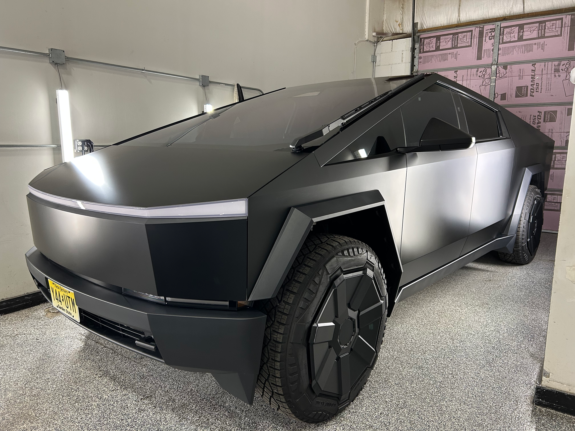 A black tesla cybertruck is parked in a garage.