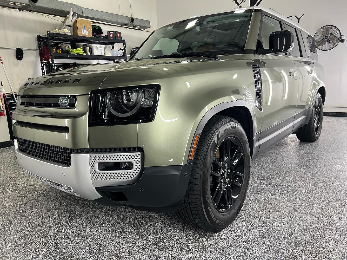 A green land rover defender is parked in a garage.