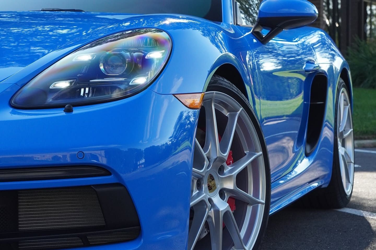 Blue sports car parked on a road, close-up of front wheel and headlight