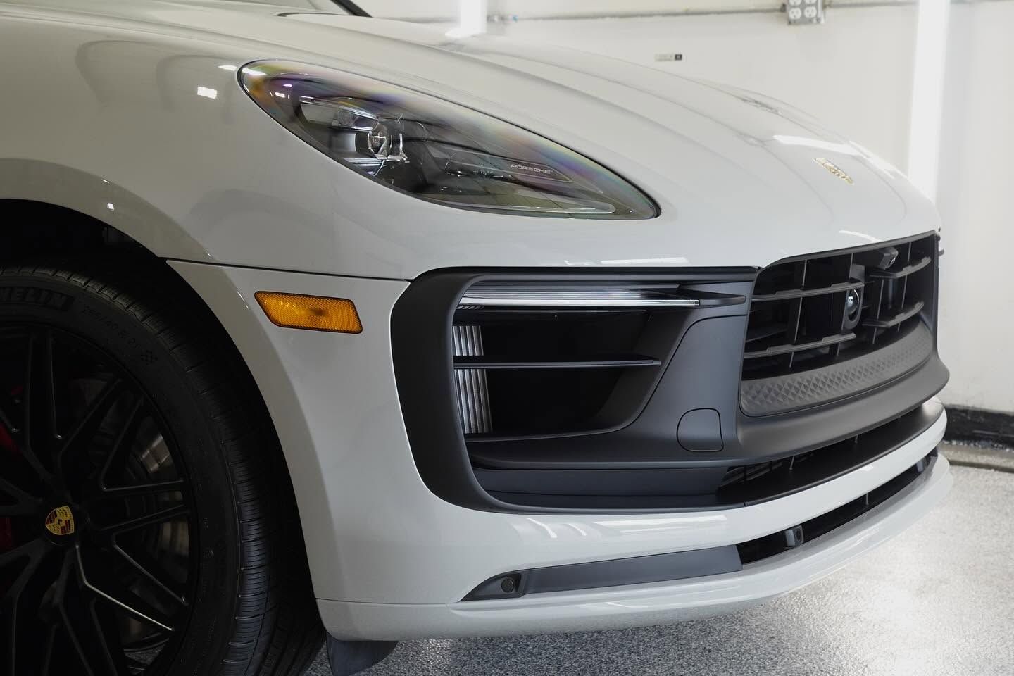 Front view of a white luxury SUV with black grille and headlights in a garage