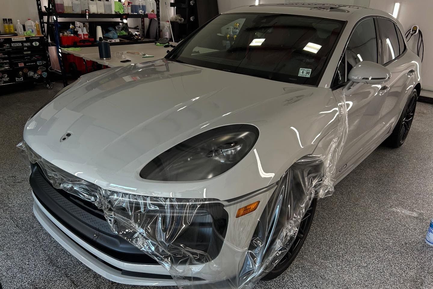 White sports sedan with a damaged front bumper in a garage workshop