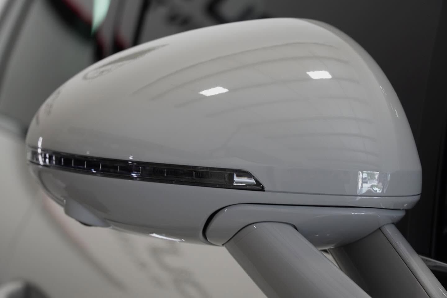 White side mirror of a car with integrated turn signal on a gray vehicle