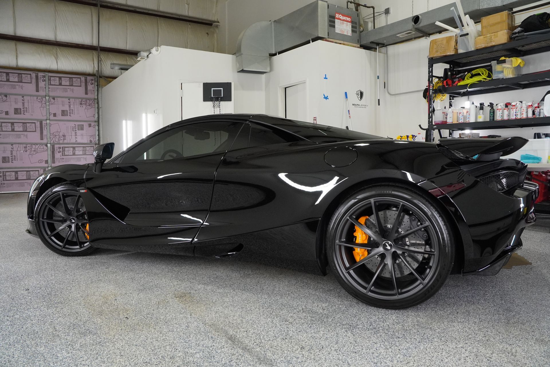 A black sports car is parked in a garage.