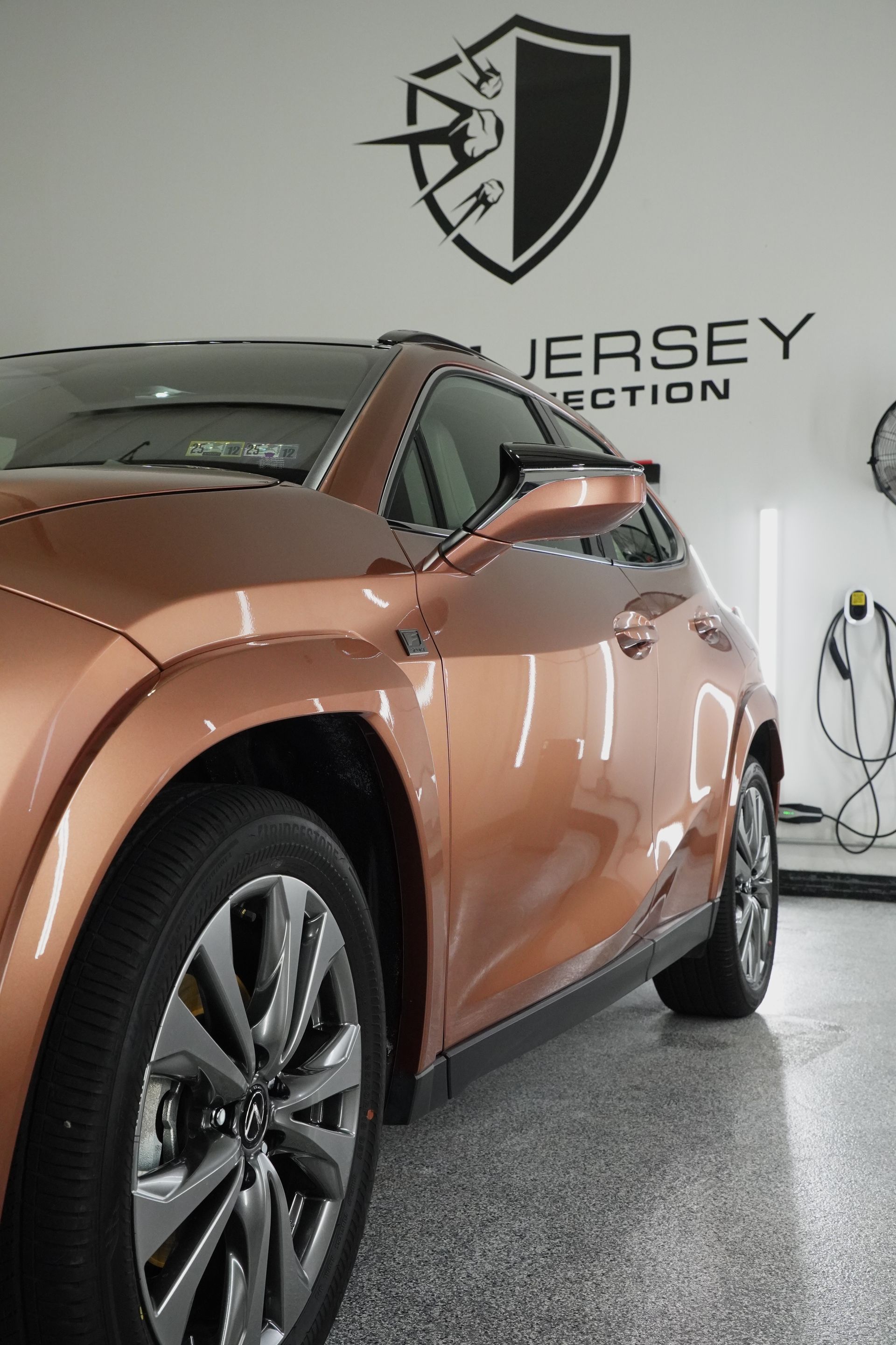 A car is parked in a garage with a logo on the wall.
