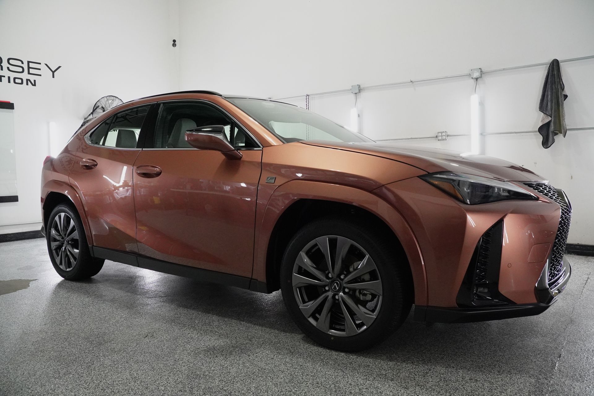 A brown lexus ux is parked in a garage.