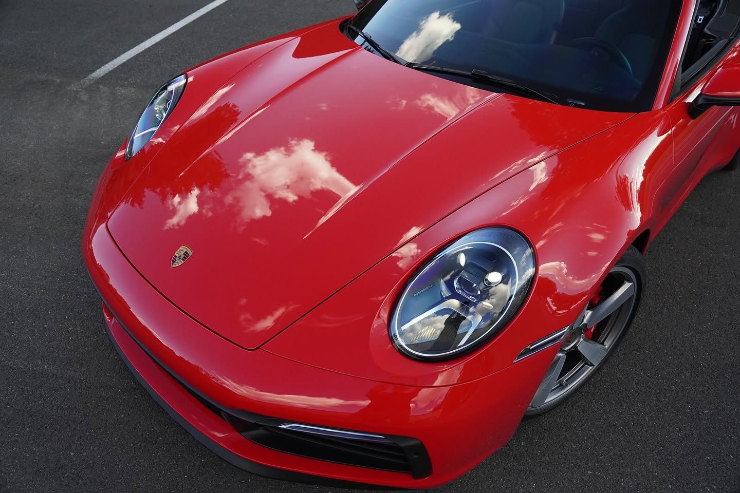 Red sports car with a glossy hood and headlights on a road
