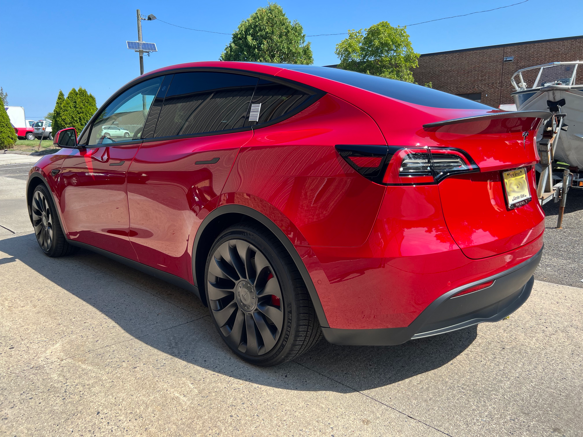 A red tesla model y is parked on the side of the road.