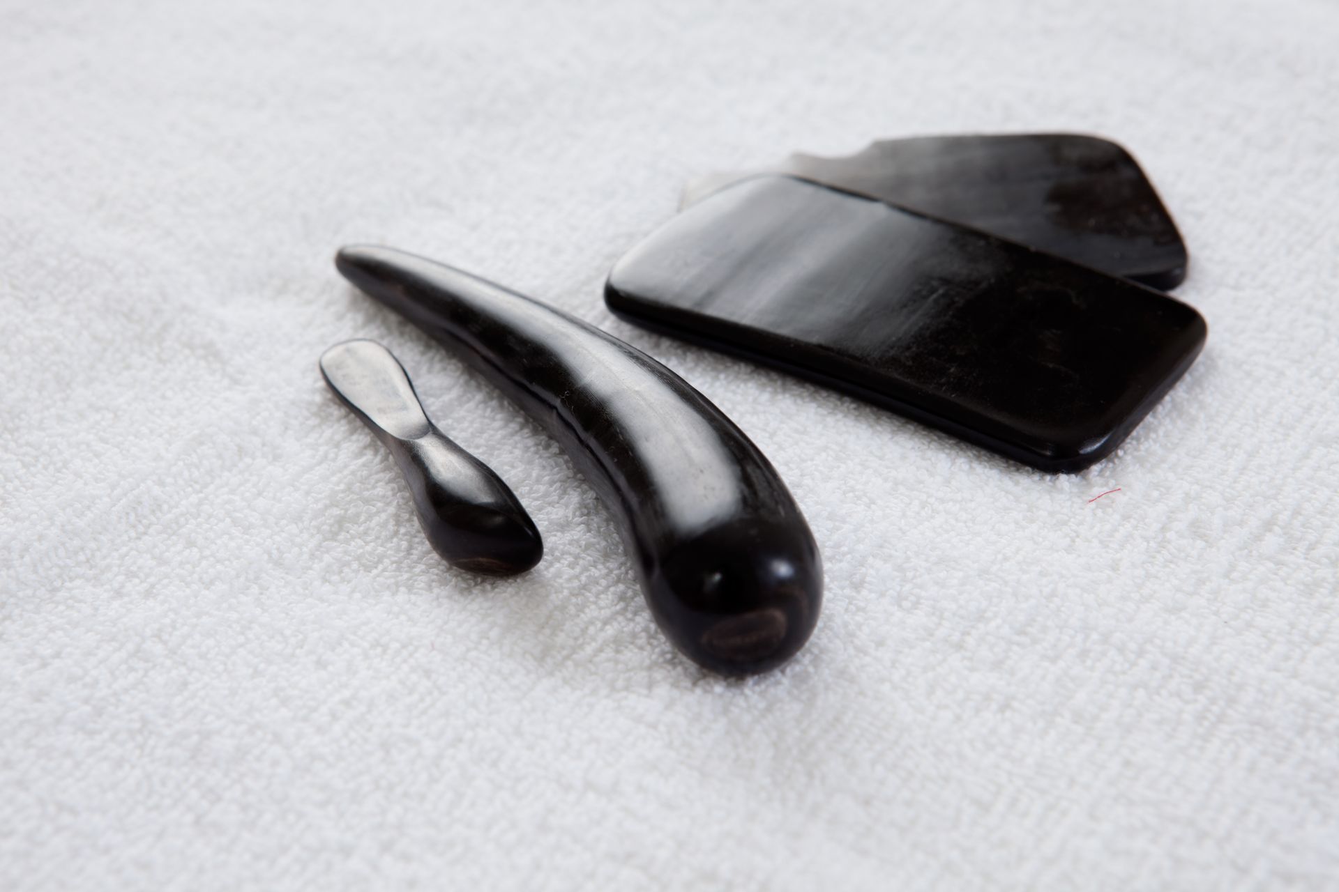 Dark wooden massage tools on a white towel, including a curved tool and two flat shapes.