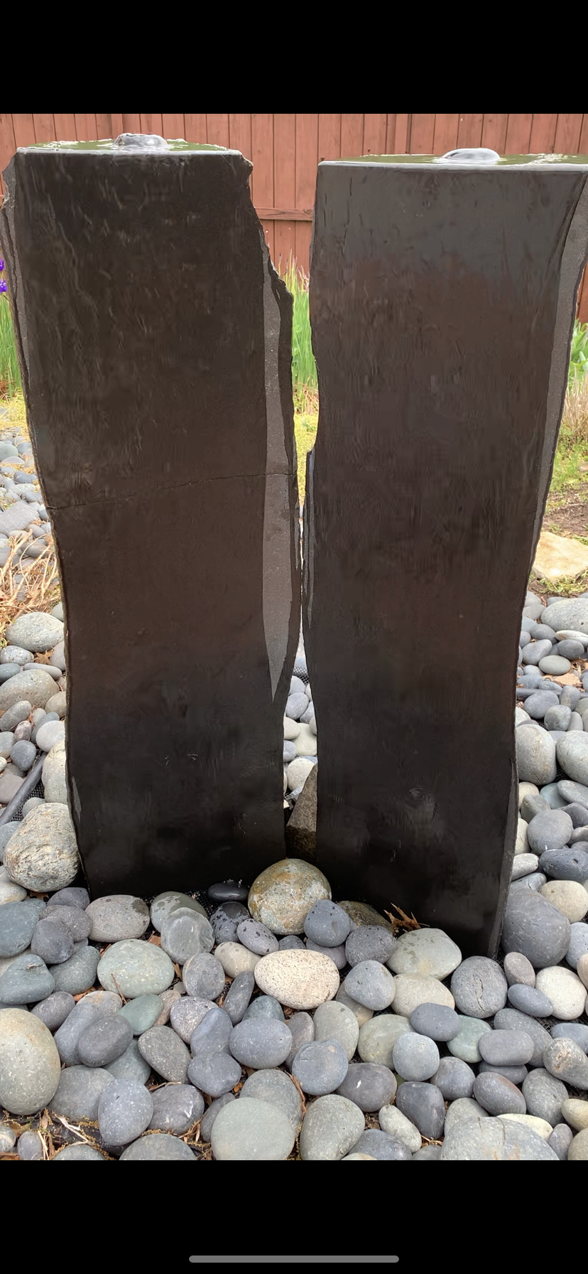 Two dark stone pillars on a bed of gray and white rocks.