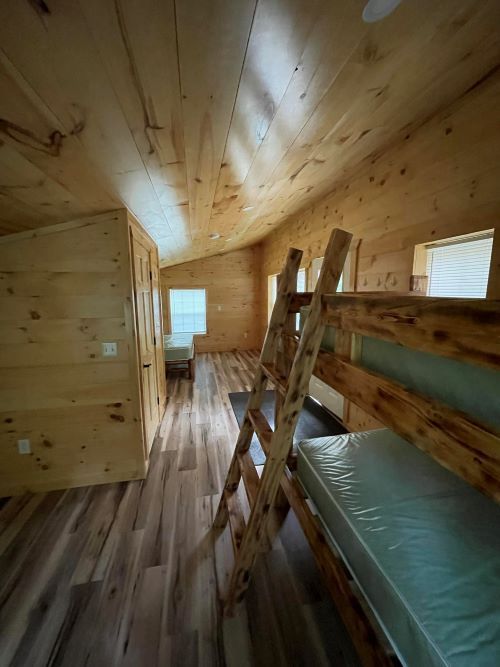 A wooden cabin with bunk beds and a ladder.