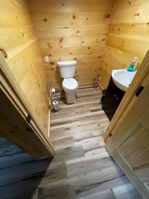 A bathroom with a toilet , sink , and wooden walls.