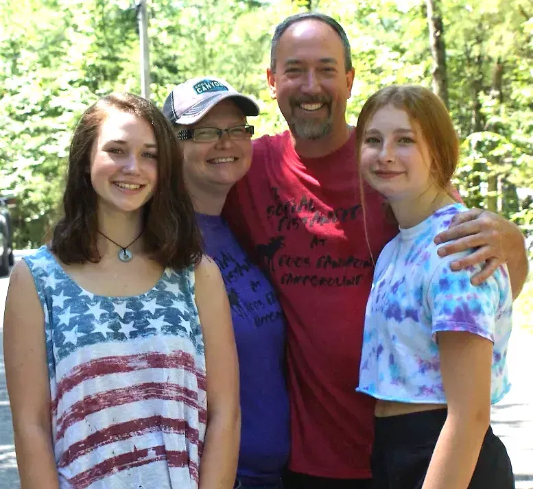 A family posing for a picture with a man wearing a red shirt that says freedom