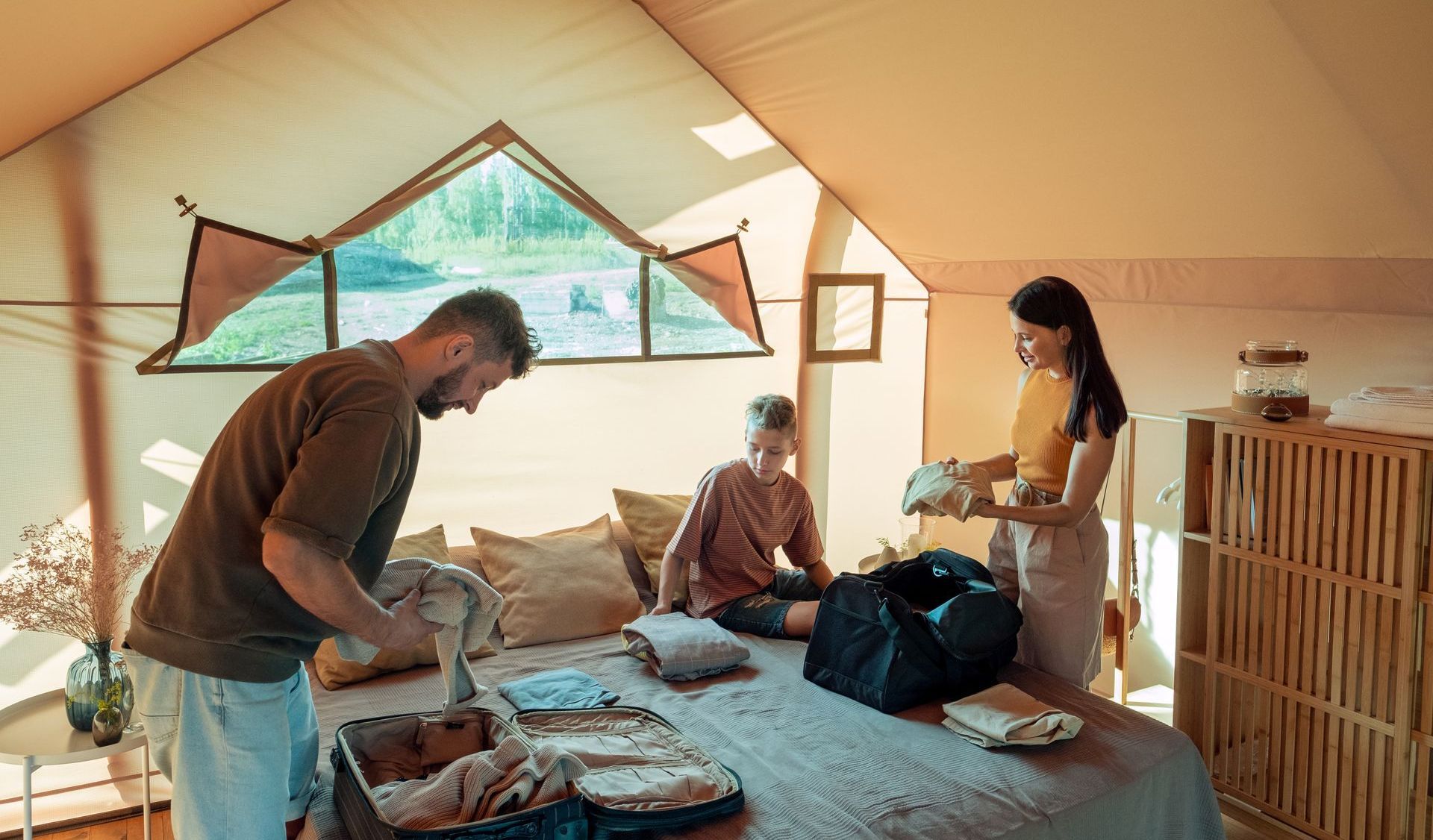 A man and a woman are packing a suitcase in a bedroom.