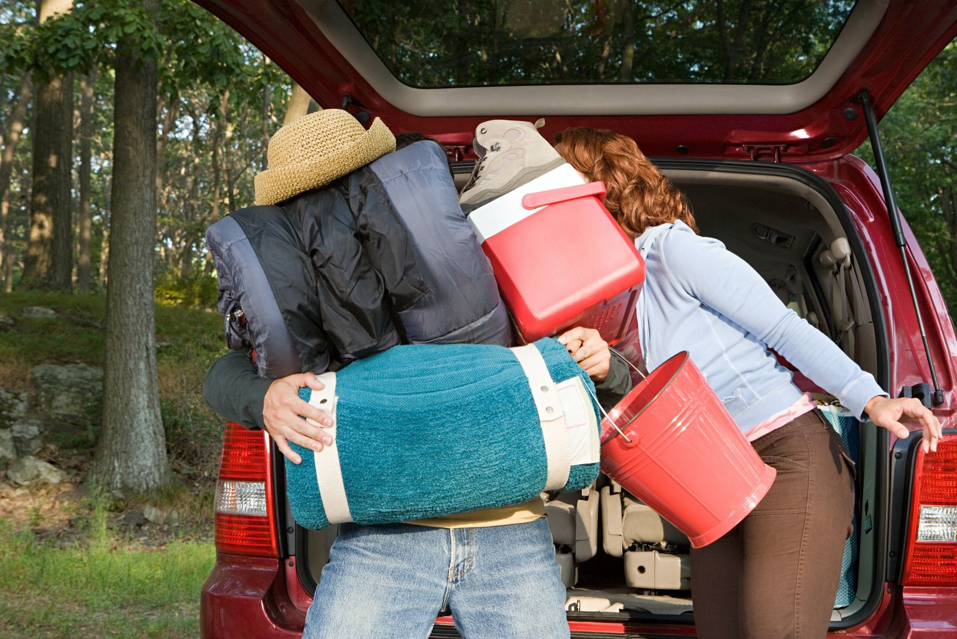 A man and a woman are loading the back of a car