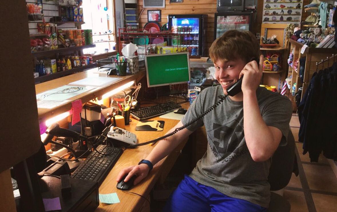 A man is sitting at a desk talking on a phone.