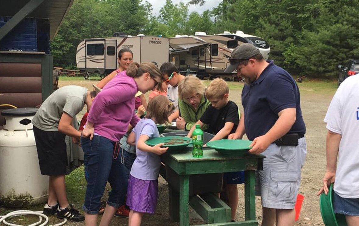 A group of people are standing around a table looking at gold pans.