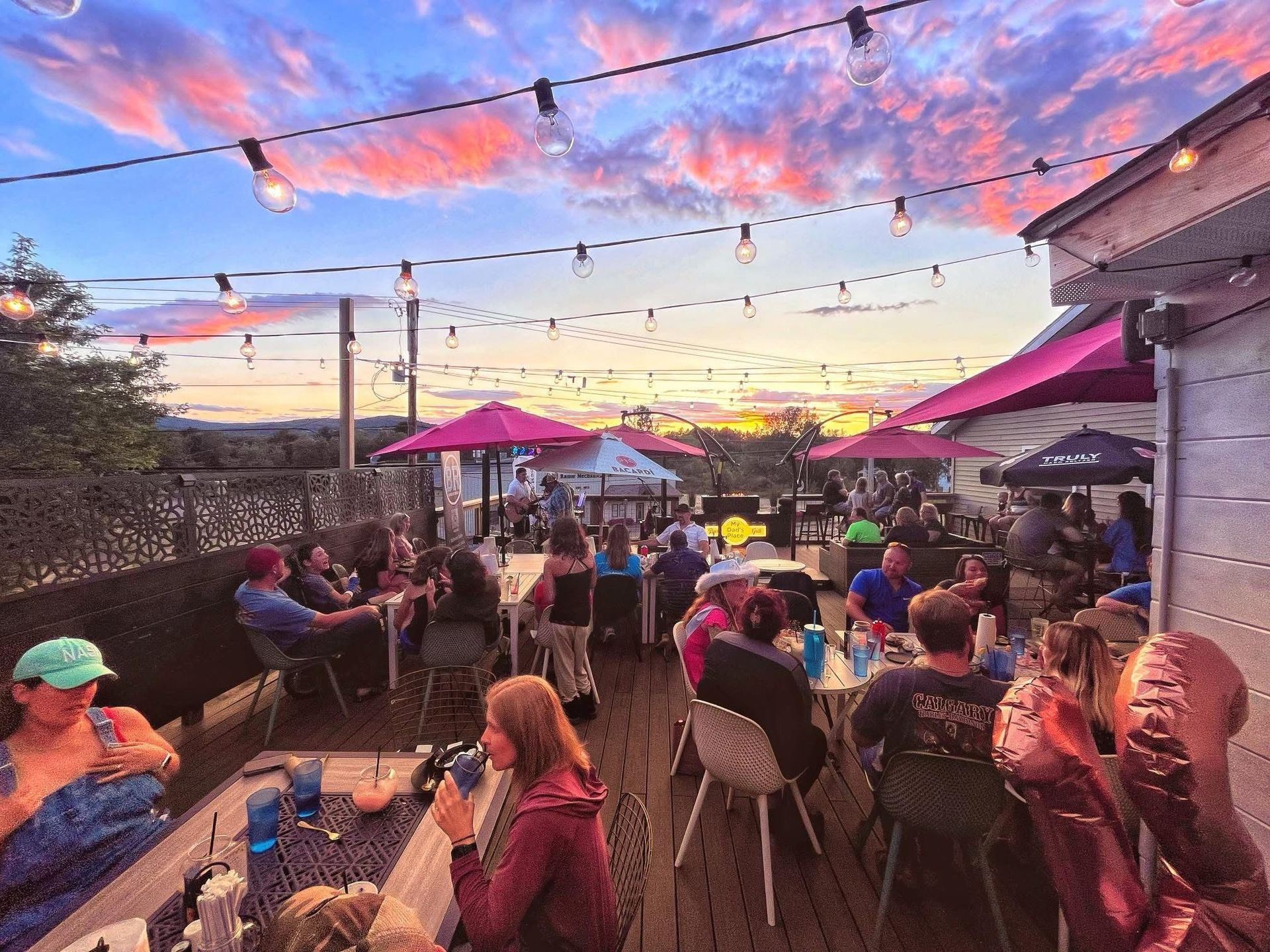 A group of people are sitting at tables on a patio at a restaurant.