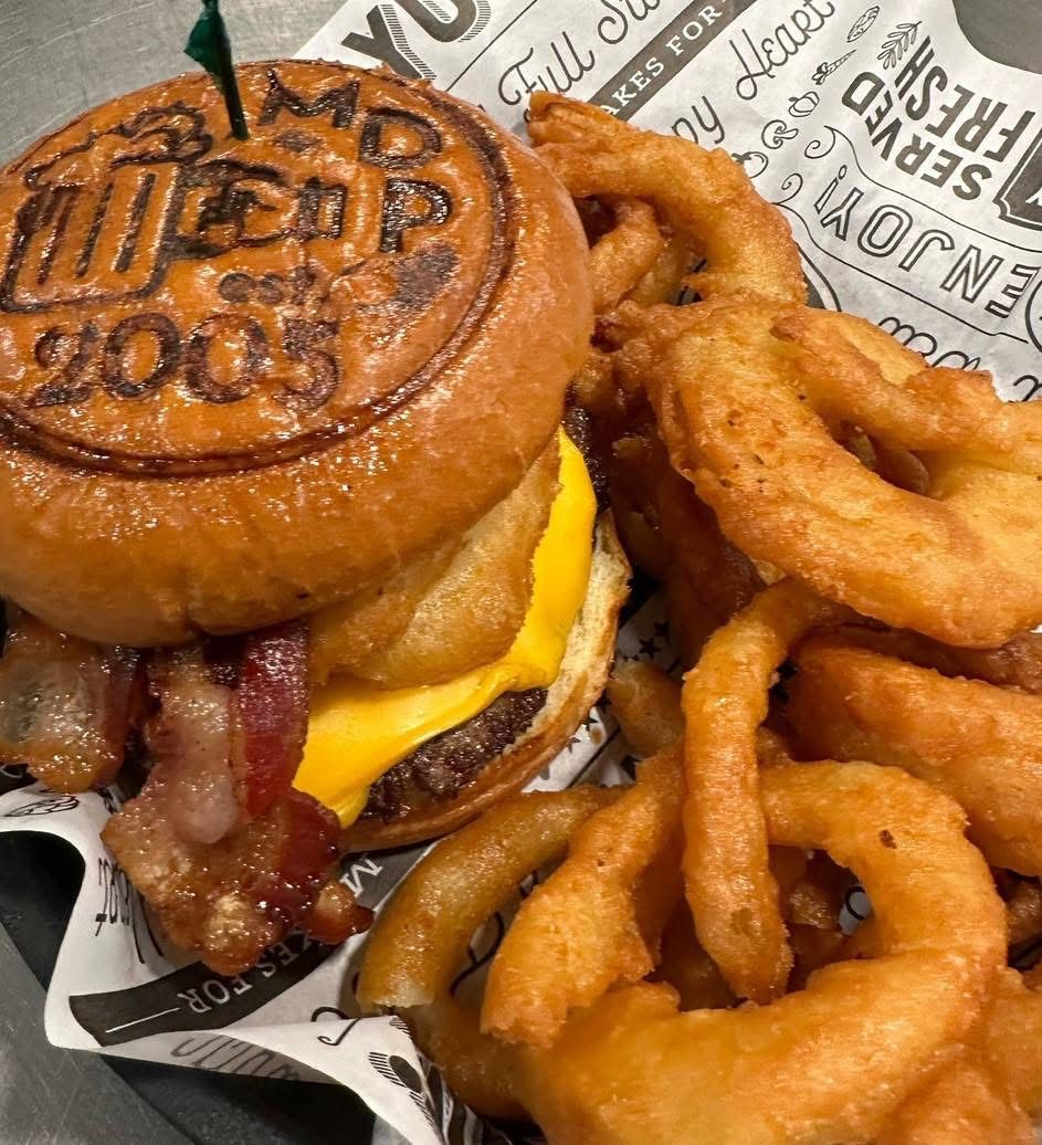 A close up of a hamburger and onion rings on a plate