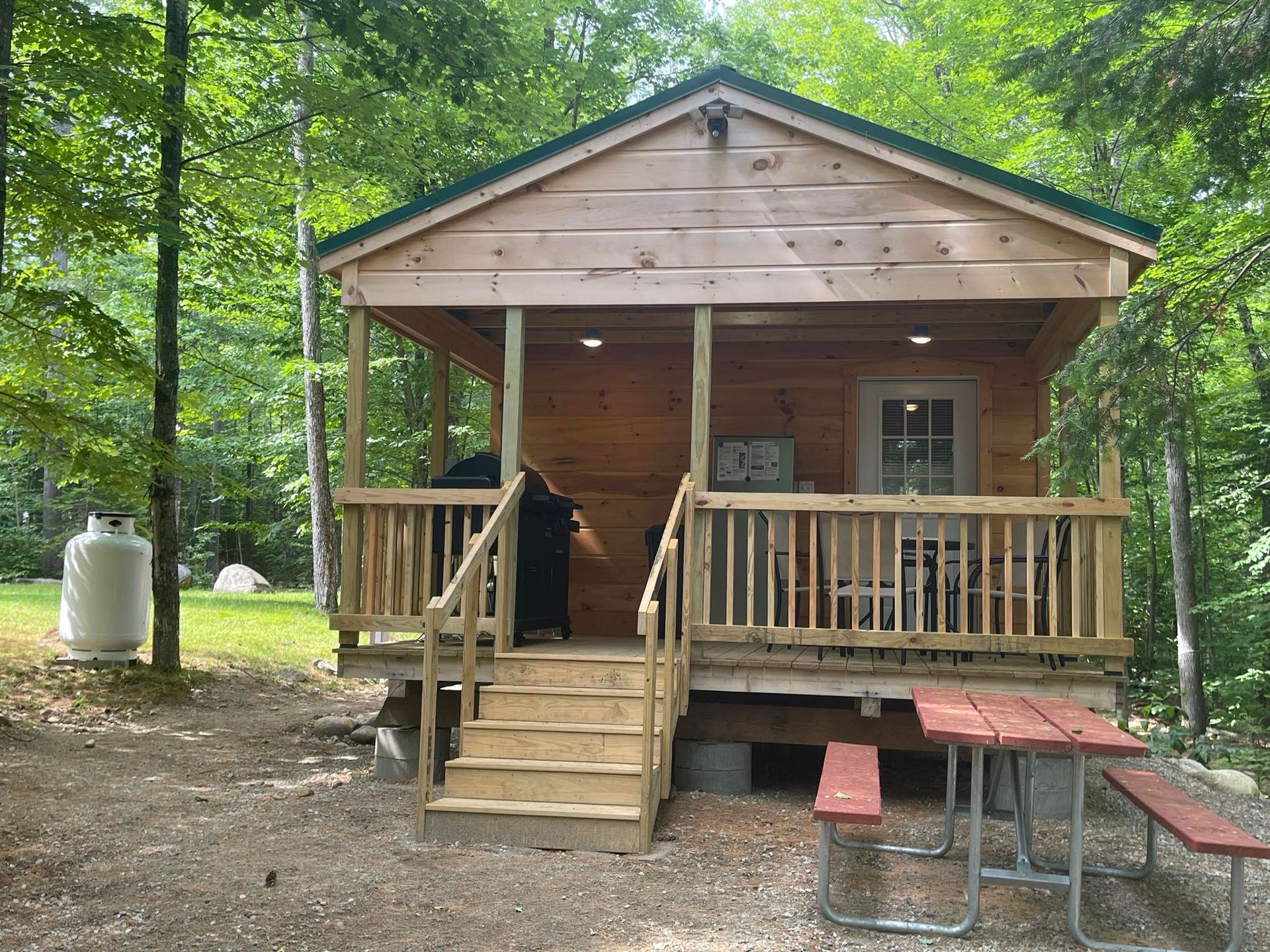 A small wooden cabin with a porch and a picnic table