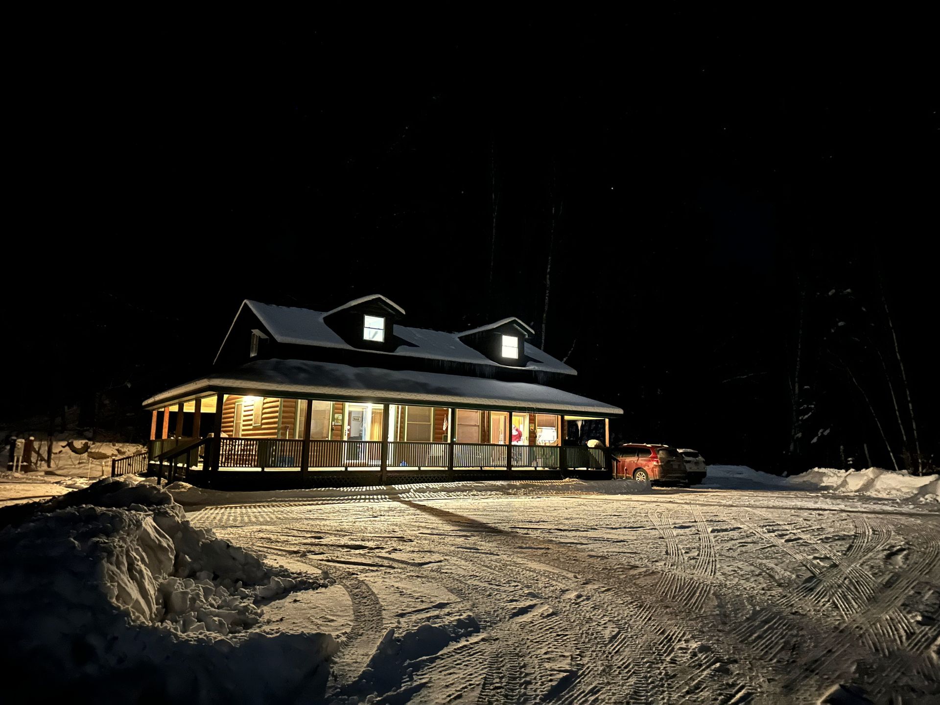 Snow-covered lodge lit warmly at night under a dark sky