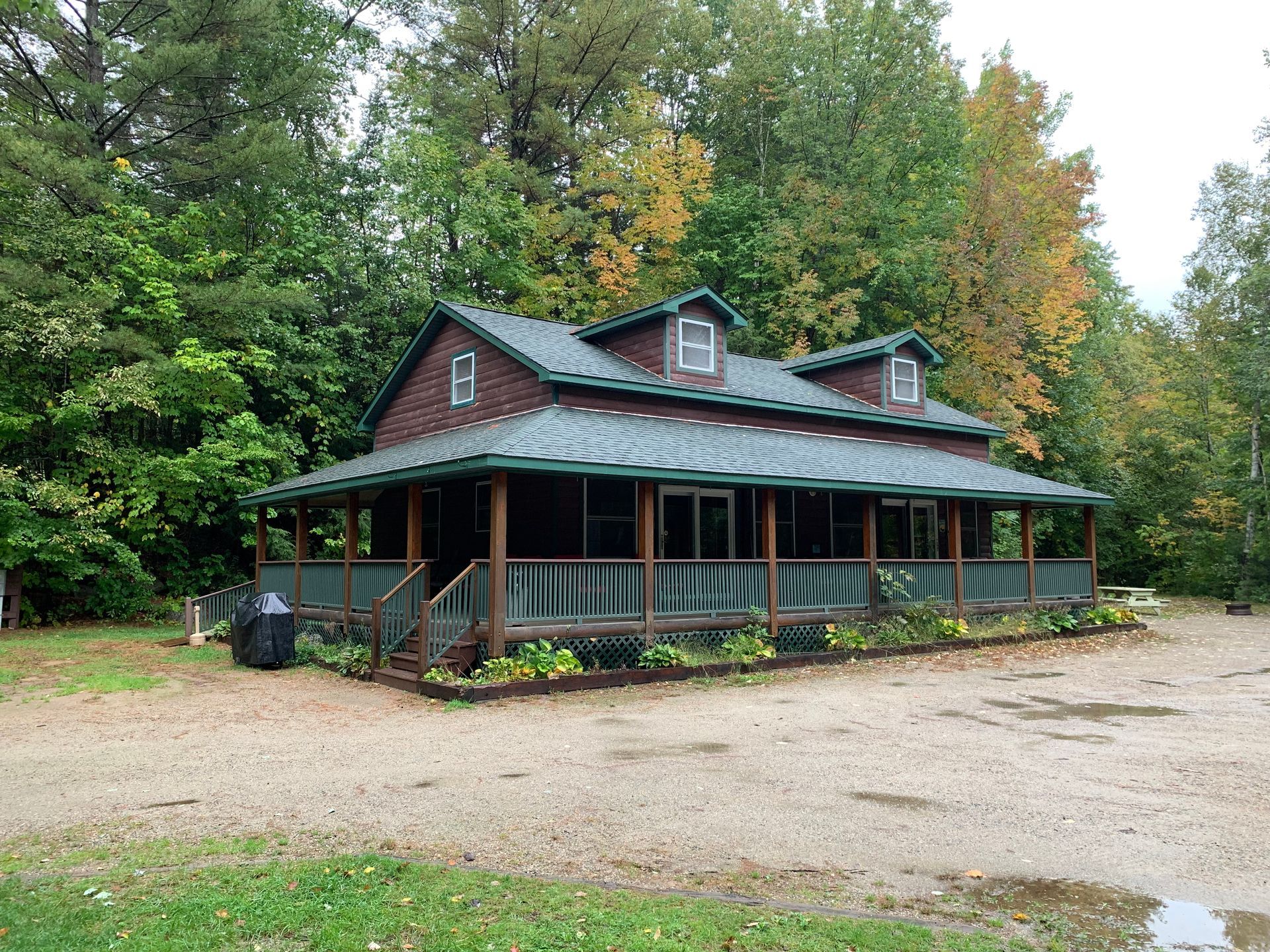 A large house with a green roof is surrounded by trees