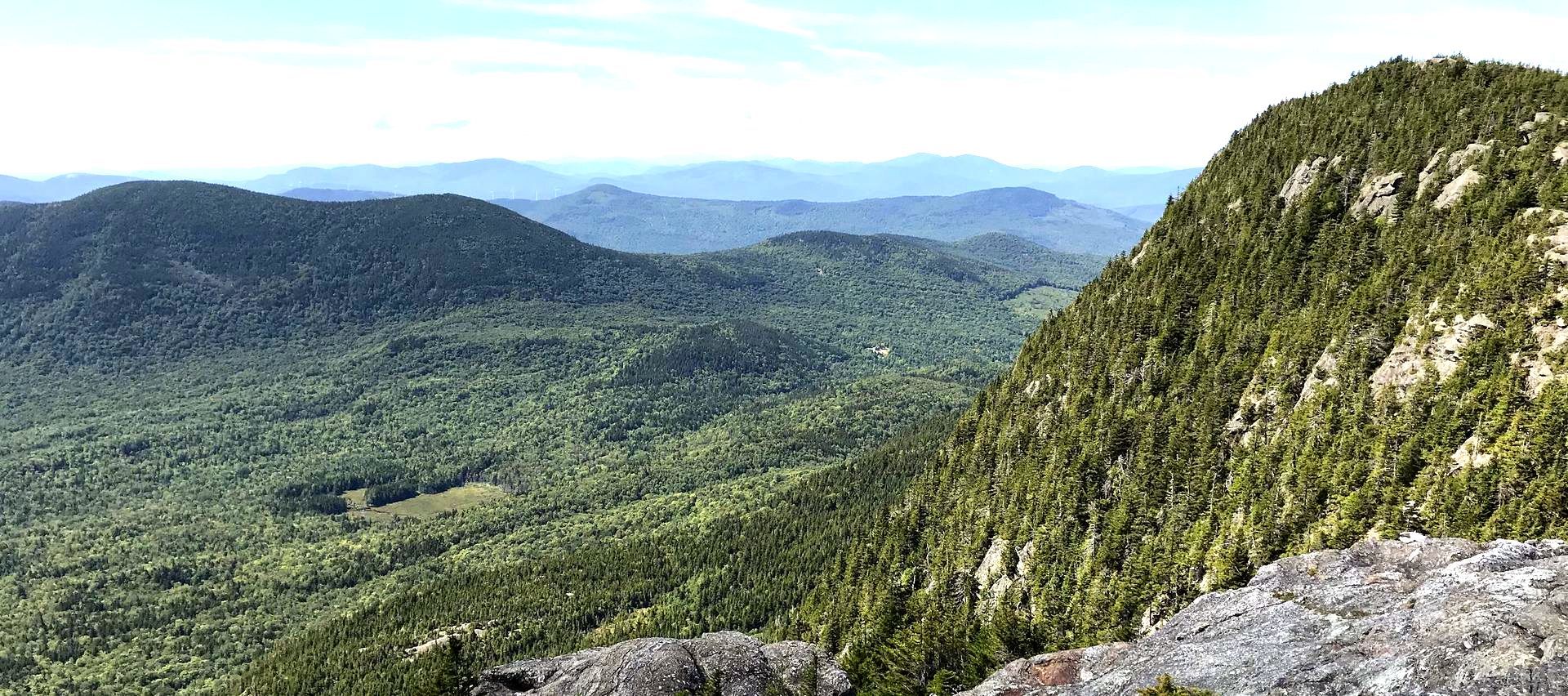 A view of a mountain covered in trees from the top of a mountain.