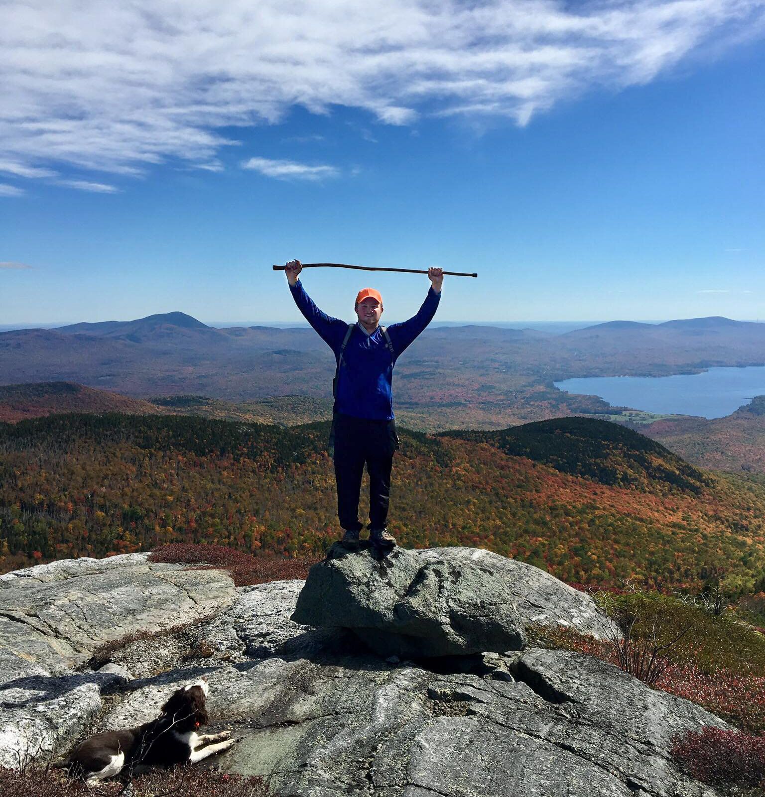 A man stands on top of a rock holding a pole over his head