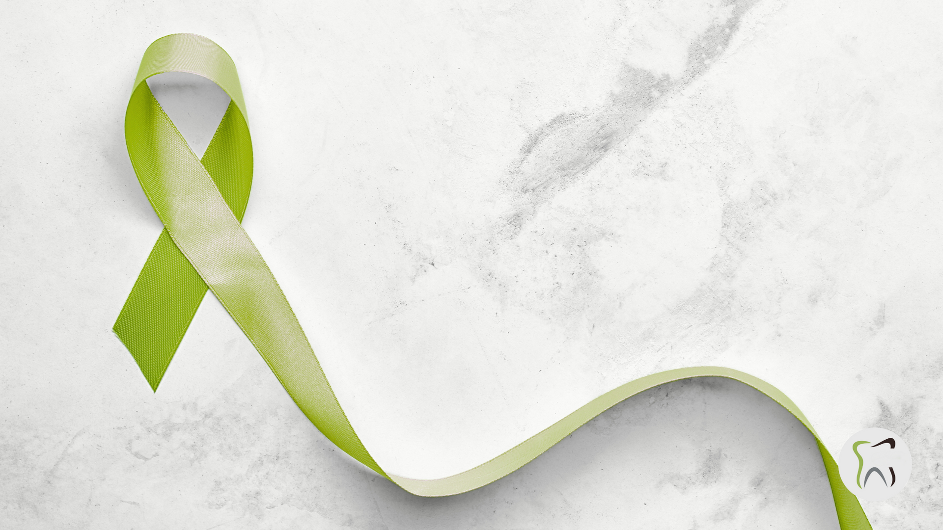 A green ribbon is laying on a white surface.