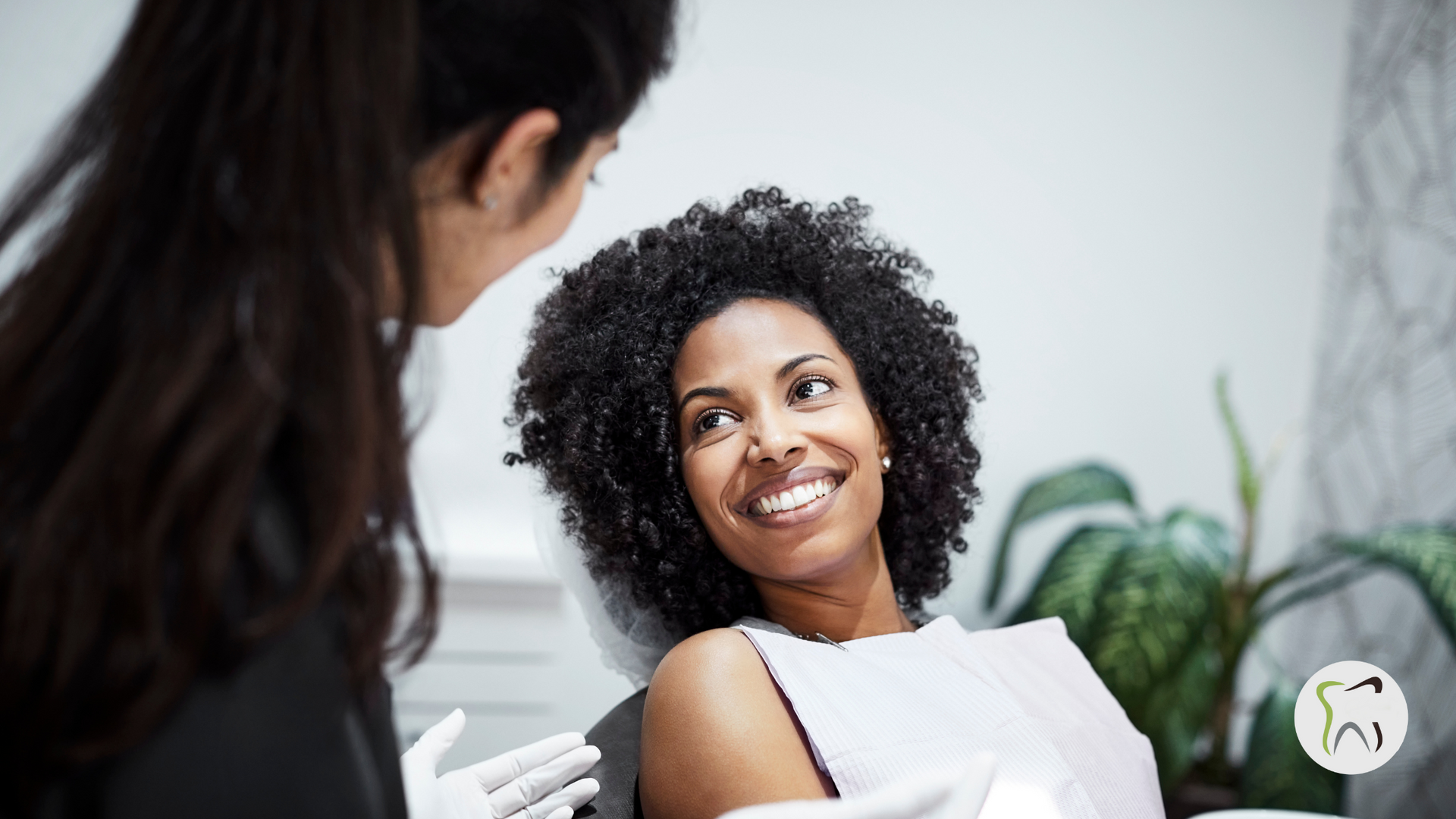A woman is sitting in a dental chair talking to a dentist.