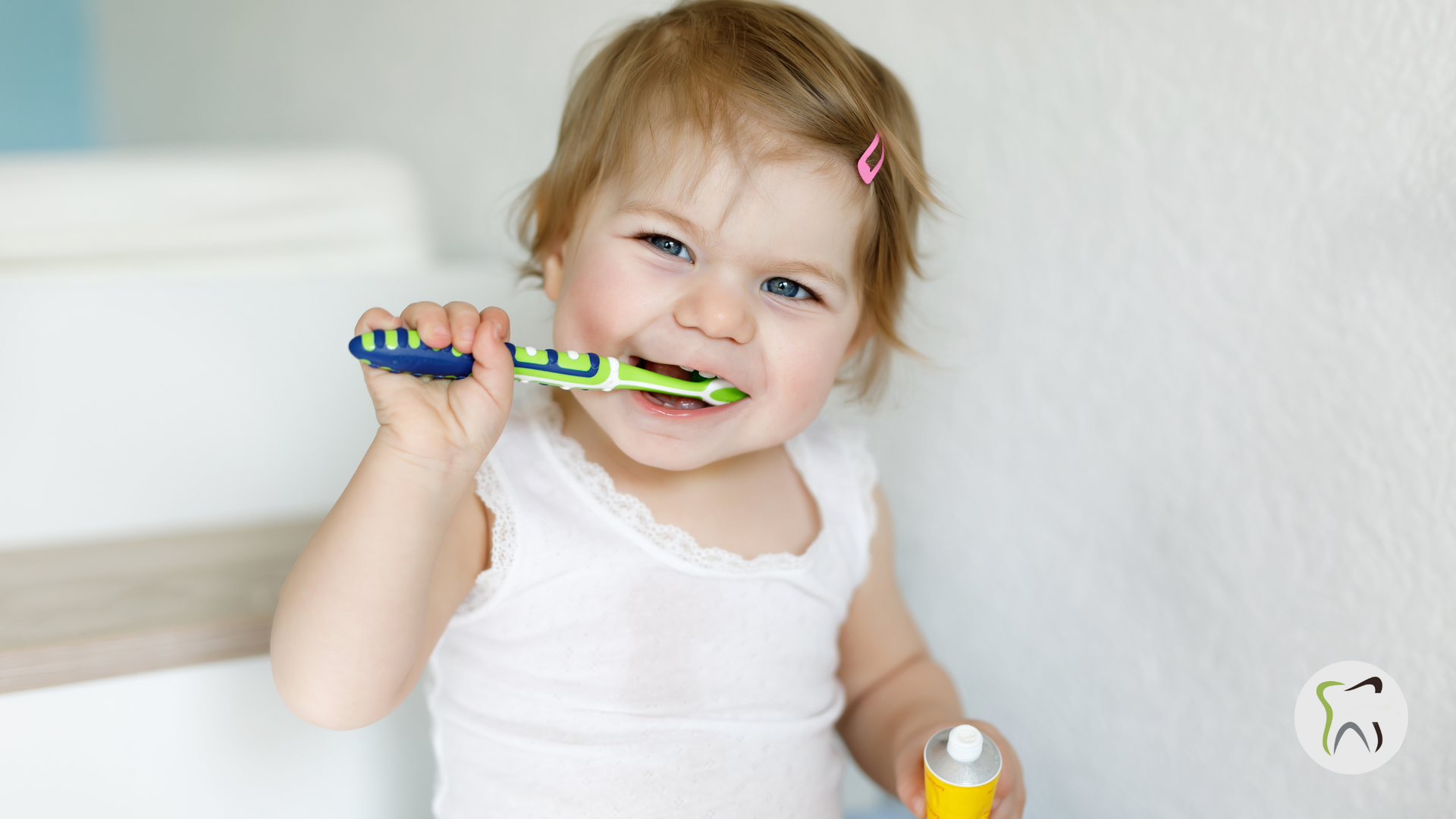 Young child brushing teeth, looking at the viewer. Holds a toothbrush, has toothpaste on mouth.