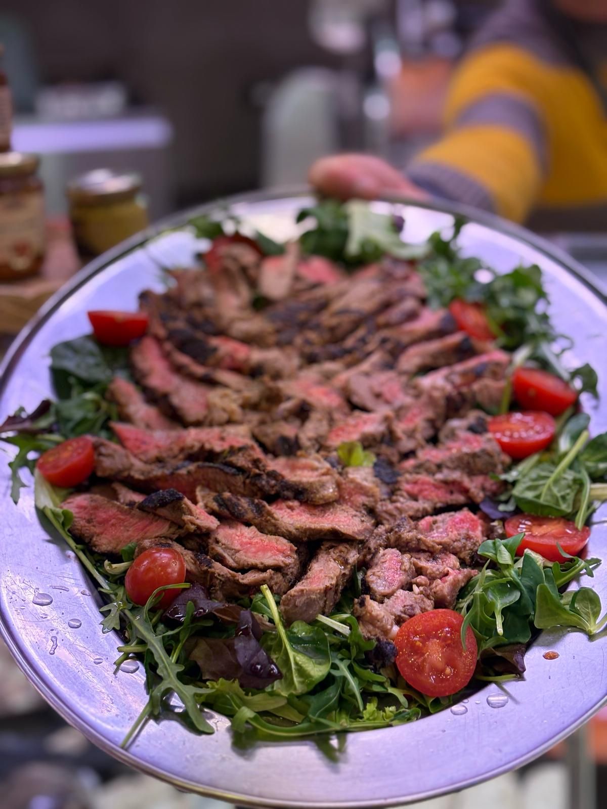 Una persona tiene in mano un piatto di carne e verdure.