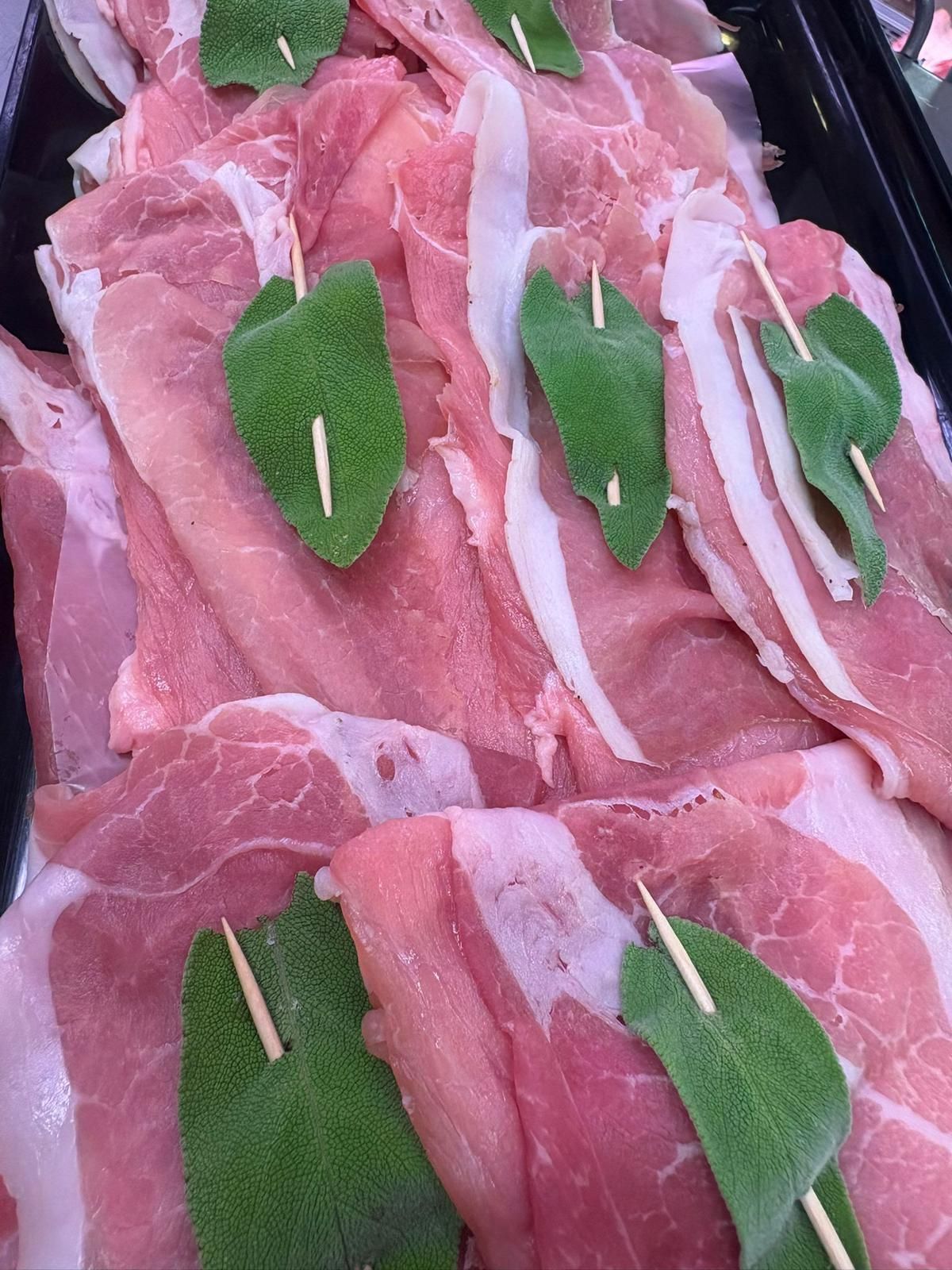Un mucchio di carne cruda con foglie verdi e stuzzicadenti.