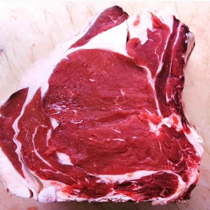 Un pezzo di manzo crudo è appoggiato su un tavolo di legno