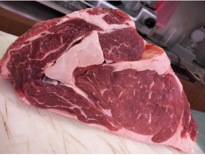 Un pezzo di carne cruda è appoggiato su un tagliere