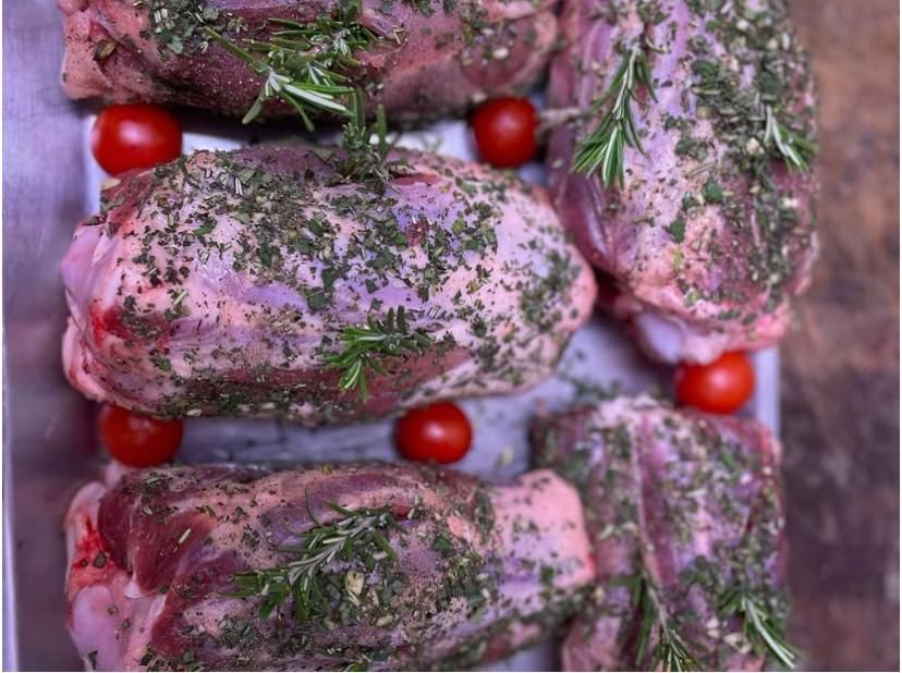 Un vassoio di carne cruda con pomodori ed erbe aromatiche su un tavolo.
