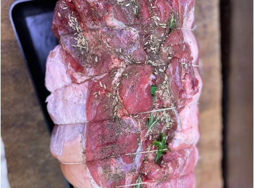 Un pezzo di carne cruda è appoggiato su un vassoio nero su un tavolo di legno.