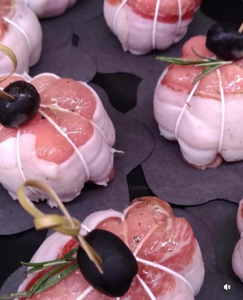 Un mucchio di carne avvolto nella pancetta con olive sopra